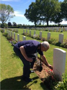 Bob Castles places a Canadian flag at Percival Haney's grave